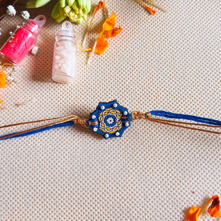 Handmade Embroidered Blue Jaipuri Beads Wooden Rakhi With Roli Chawal For Brother - Flat Lay with Decorative Background