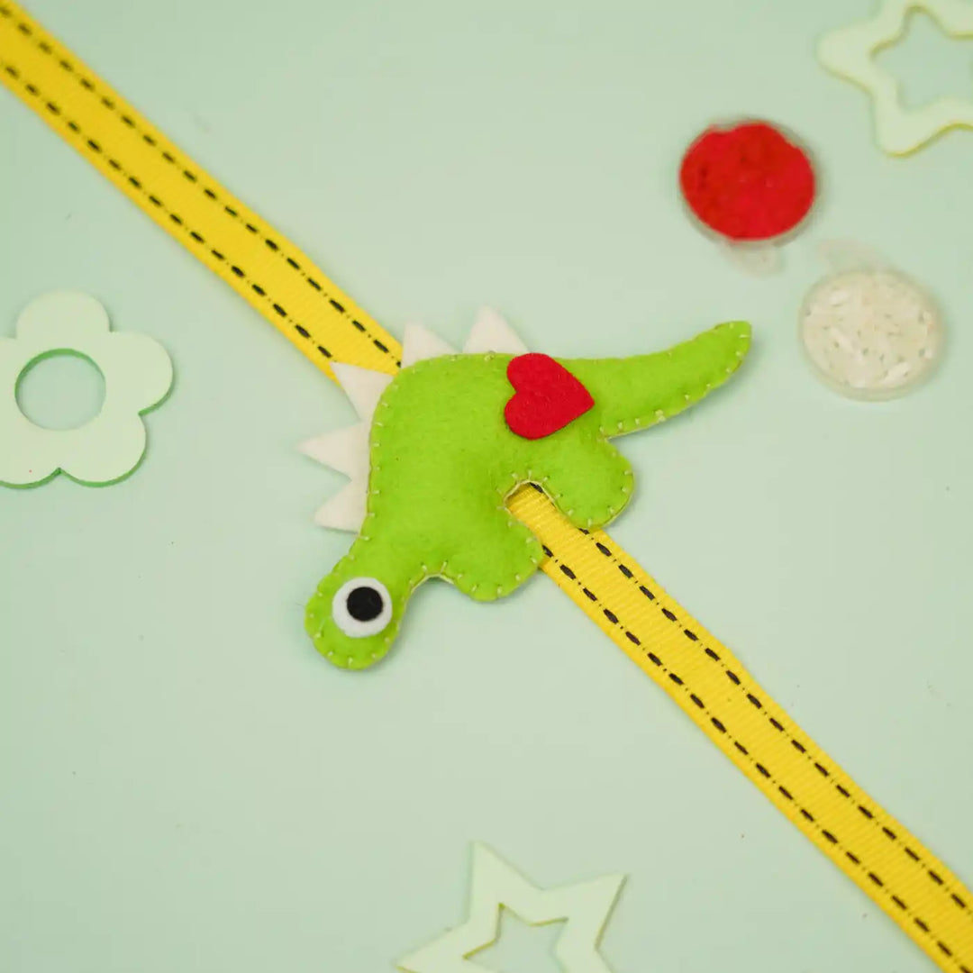Handmade Dino Theme Felt Kids Rakhi With Roli Chawal - Flat Lay with Accessories