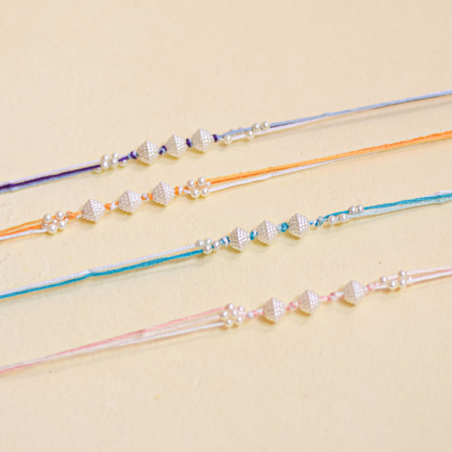 Handmade Trimurty Pearl Rakhi With Roli Chawal - Close-up of four bracelets