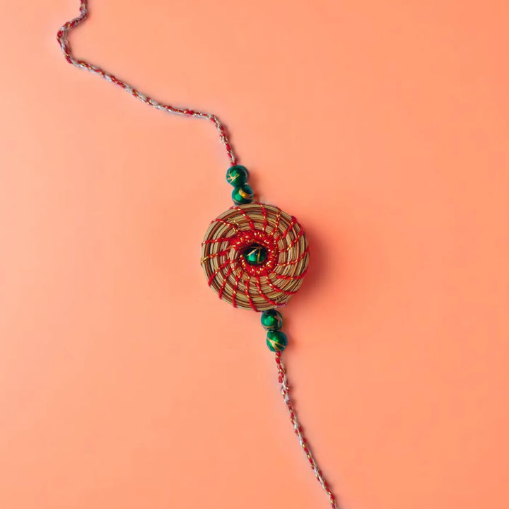 Eco Friendly Handmade Green Breads Pine Needle Rakhi With Pouch And Roli Chawal - Flat Lay Front View