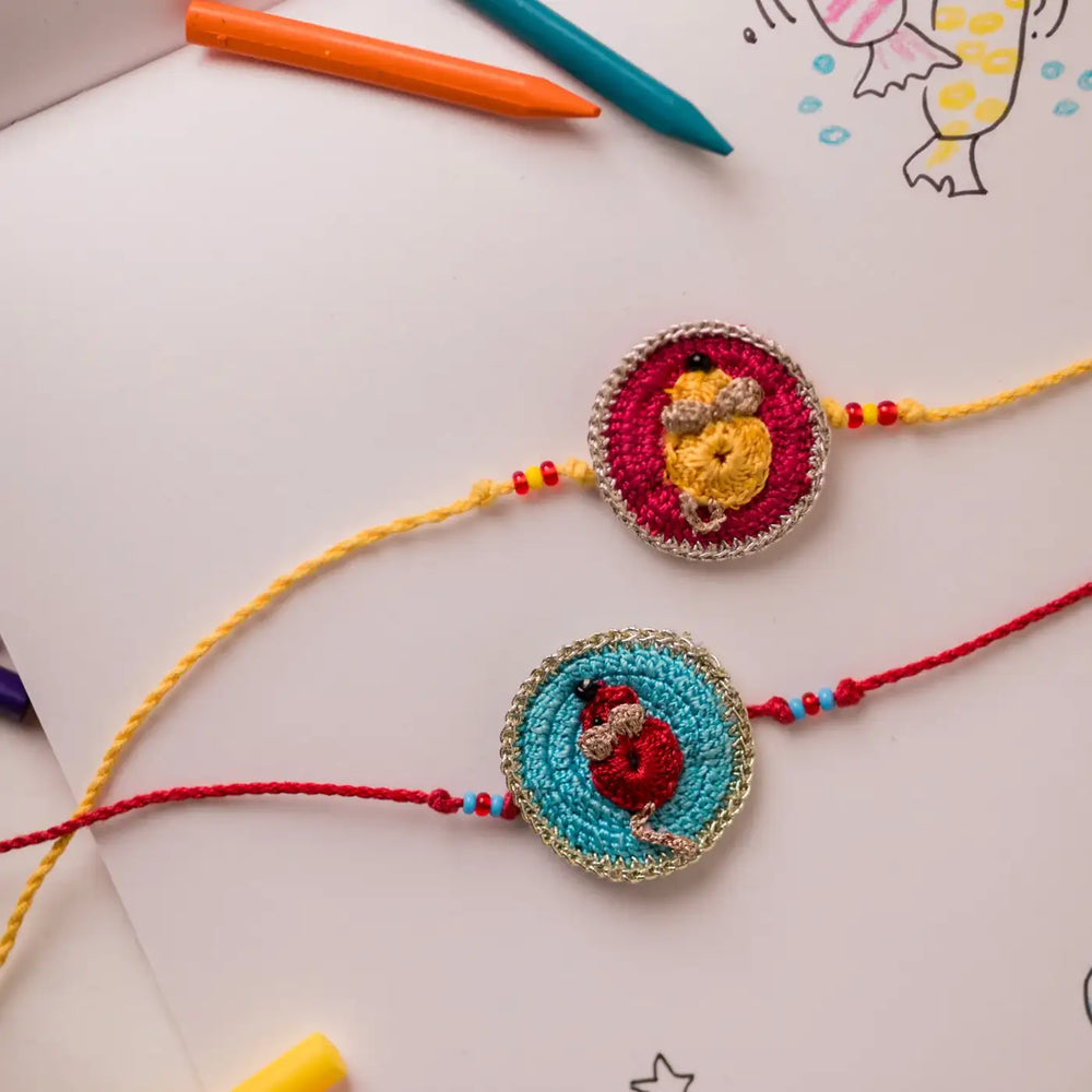 Handmade Crochet Cute Mouse Theme Kids Rakhi With Roli Chawal Set Of 2 - Flat lay on children's drawing