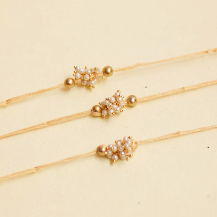 Handmade Single Bajra Ghungroo And Pearl Rakhi With Roli Chawal - Close-up of Three Bracelets