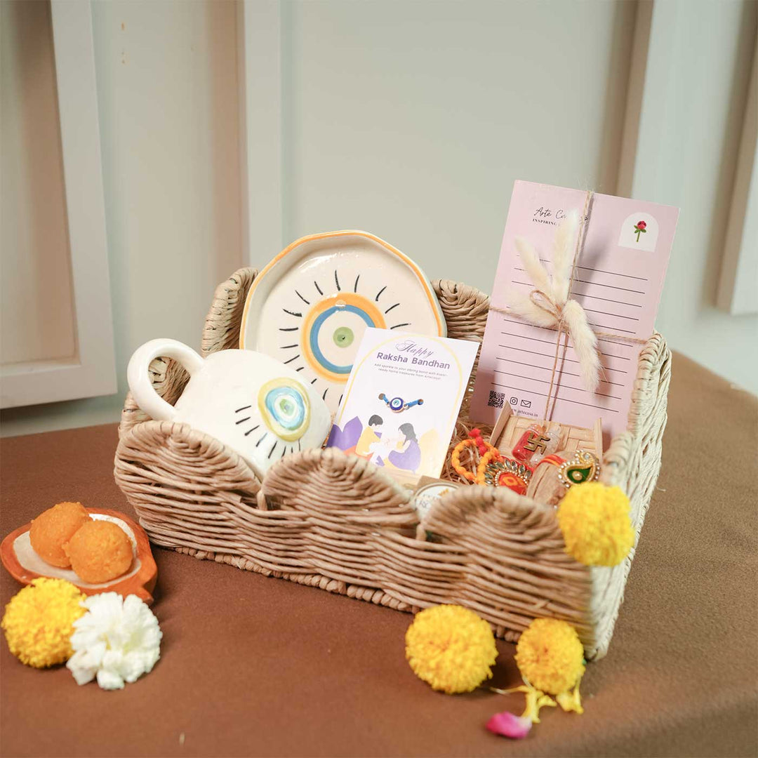 Personalized Handmade Evil Eye Design Guardians Blessing Rakhi Hamper Includes 1 Basket 1 Cup And Saucer 1 Rakhi 1 Roli Chawal And 1 Message Card - Basket with cup, plate, and cards