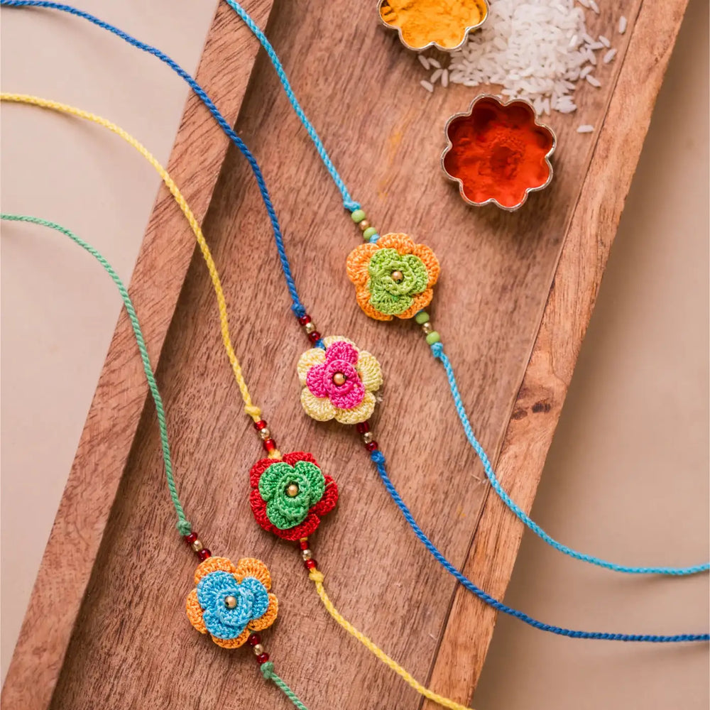 Handmade Crochet Multicolor Roses Rakhi With Roli Chawal Set Of 4 - Flat Lay with Spices