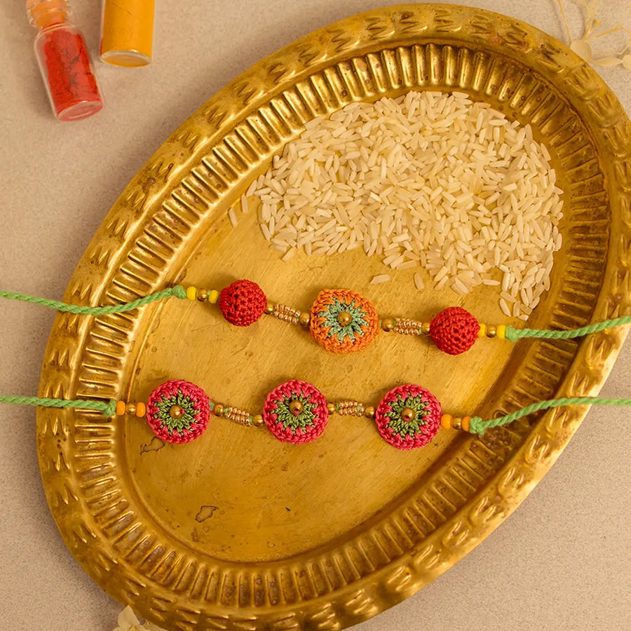Handmade Crochet Multicolour Ananta Rakhi With Roli Chawal Set Of 2 - Close-up of two bracelets on tray