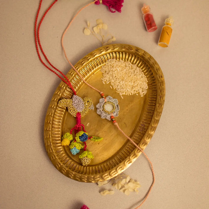 Handmade Crochet Paakhi Seepi Bhaiya Bhabhi Rakhi With Roli Chawal Set Of 2 - Flat Lay on Brass Plate