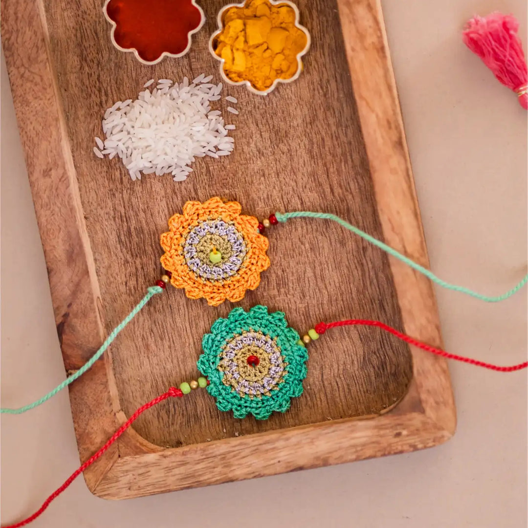 Handmade Crochet Green And Yellow Seher Rakhi With Roli Chawal Set Of 2 - Top View with Rakhi Strings Extended