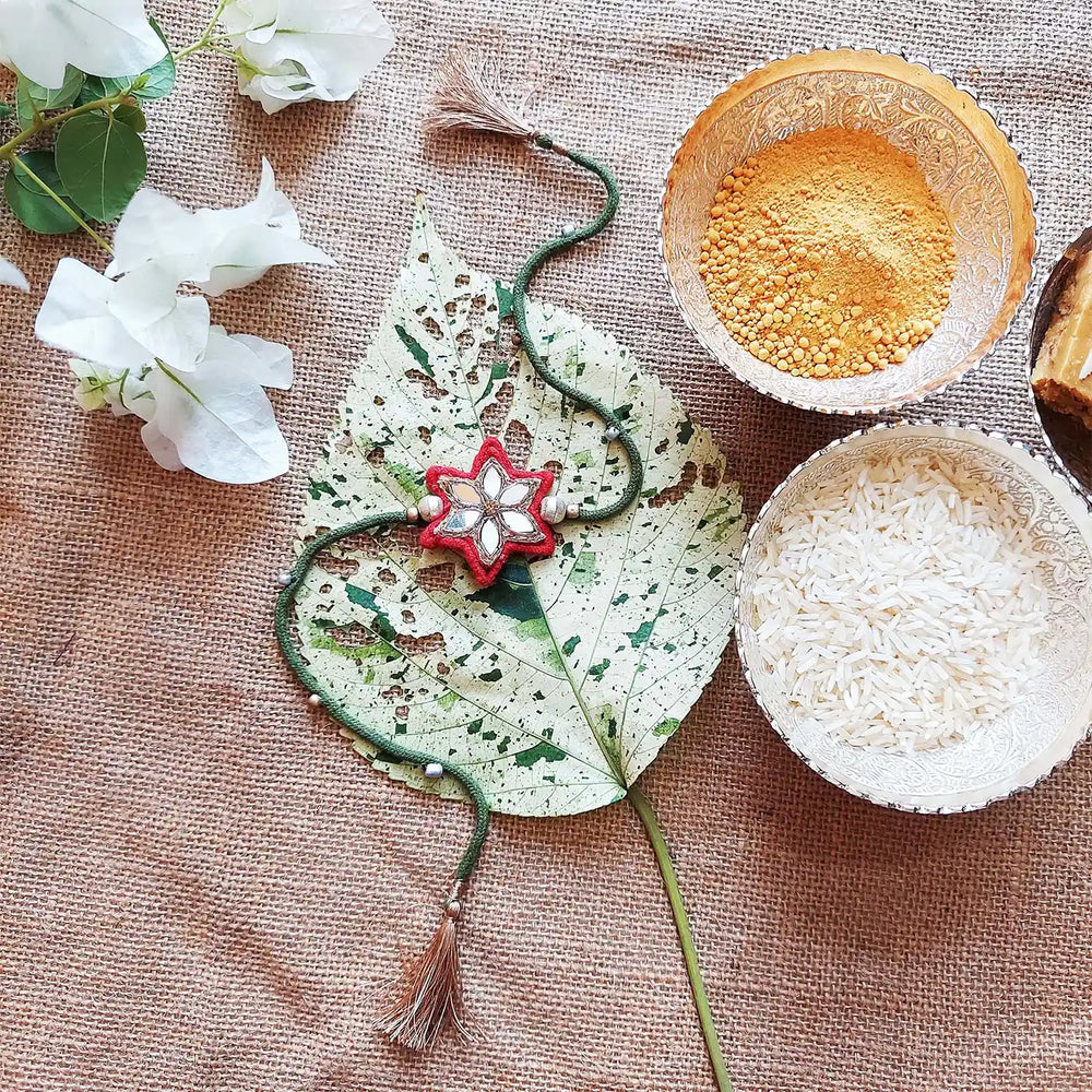 Handmade Mirror Work Flower Rakhi With Roli Chawal - Styled Flat Lay with Accessories