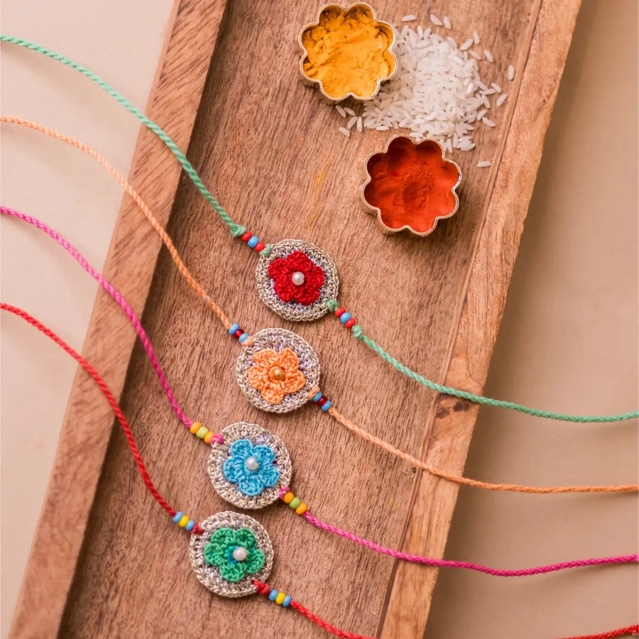 Handmade Crochet Multicolor Embellished Geraniums Rakhi With Roli Chawal Set Of 4 - Flat Lay Front View