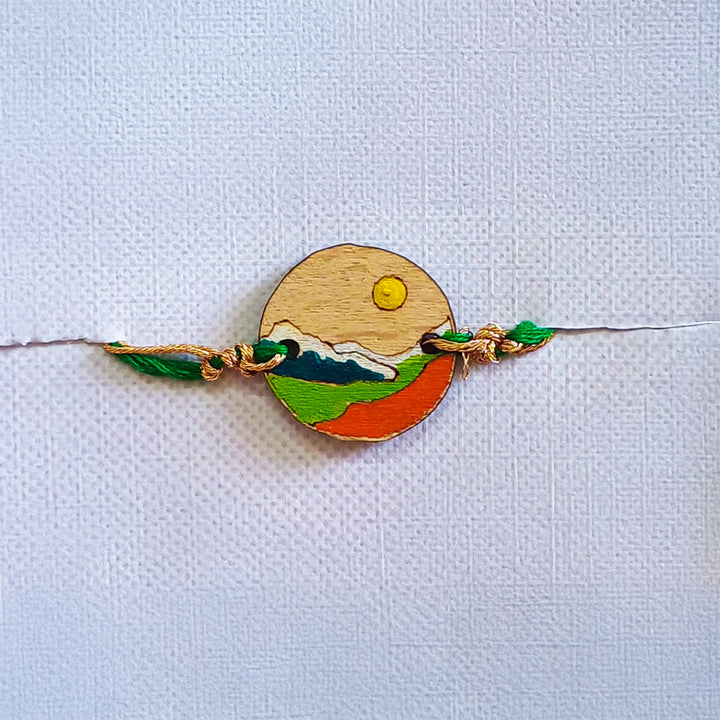 Handmade Mountain Sun And Snow Wooden Rakhi With Roli Chawal For Brother - Front View with Green Thread