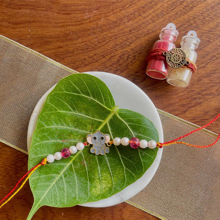 Handmade Elephant Design Metal Kids Rakhi - Full View with Decorative Background