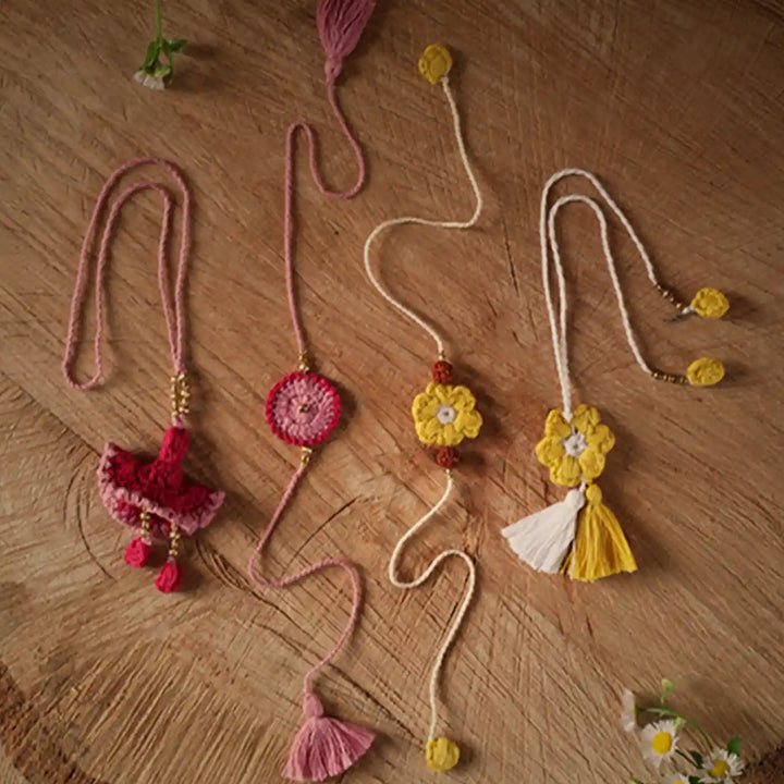 Handmade Crochet Pink And Yellow Bhaiya Bhabhi Rakhi With Roli Chawal Set Of 4 - Flat Lay View with Natural Light