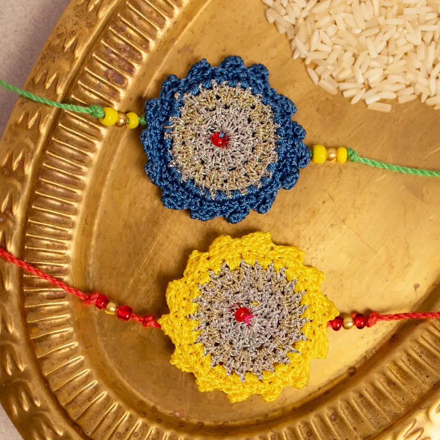 Handmade Crochet Blue And Yellow Seher Rakhi With Roli Chawal Set Of 2 - Close-up of two crochet rakhis