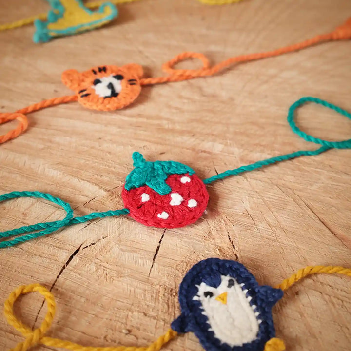 Handmade Crochet Dino Tiger Strawberry And Penguin Kids Rakhi With Roli Chawal Set Of 4 - Close-up on Wood Surface