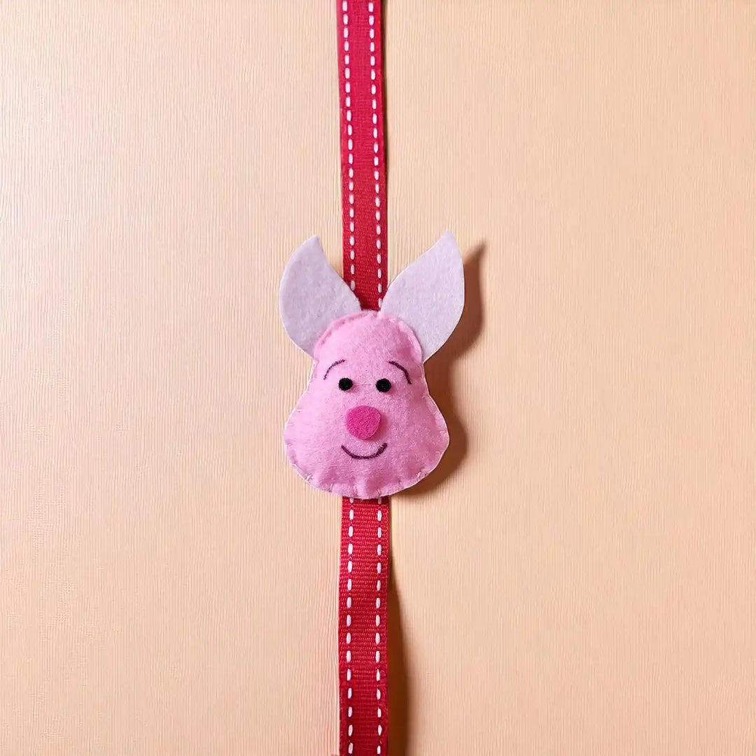 Handmade Piglet Theme Felt Kids Rakhi With Roli Chawal - Front View with Full Ribbon