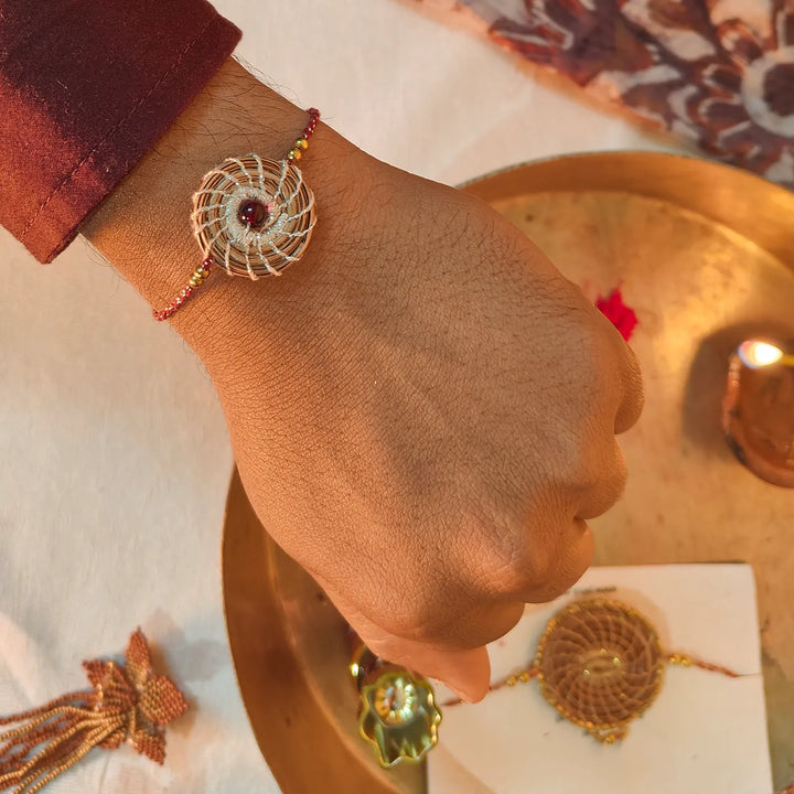 Eco Friendly Handmade Silver And Red Pine Needle Rakhi With Pouch And Roli Chawal - On Wrist Wearing View