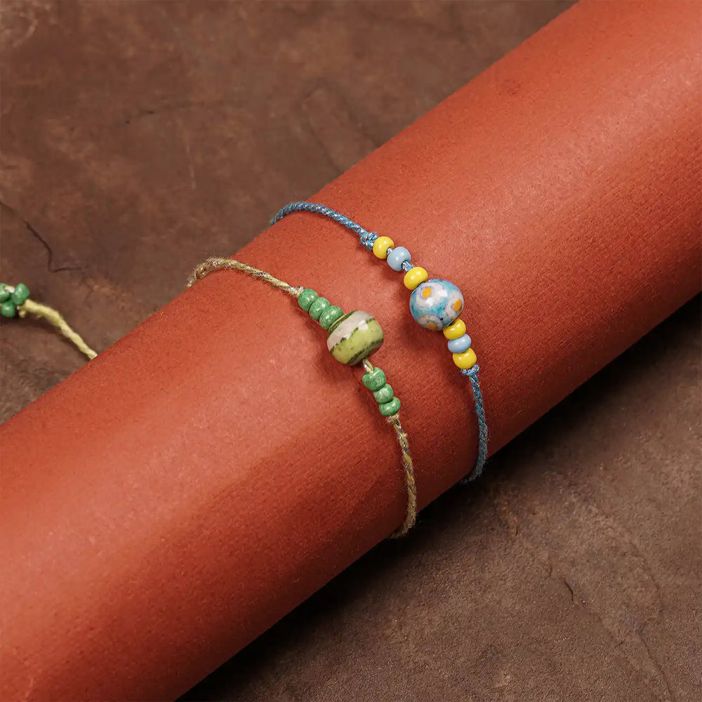 Handmade Blue Pottery Bead Rakhi With Roli Chawal Set Of 2 - Wrapped Around Cylindrical Object