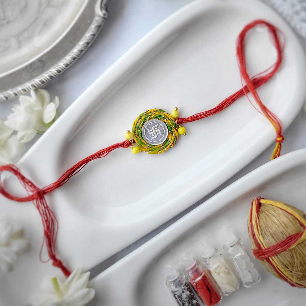 Handmade Swatik Design Silver Rakhi Hamper With Roli Chawal For Brother 1 - Full Rakhi on display plate