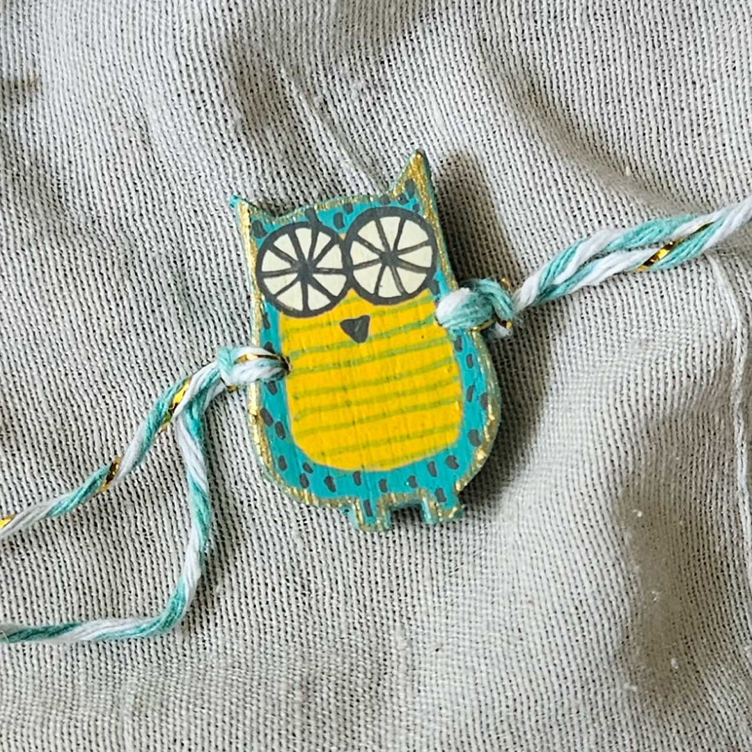 Handpainted Quirky Wooden Rakhi With Roli Chawal - Close-up of Blue Owl Bracelet