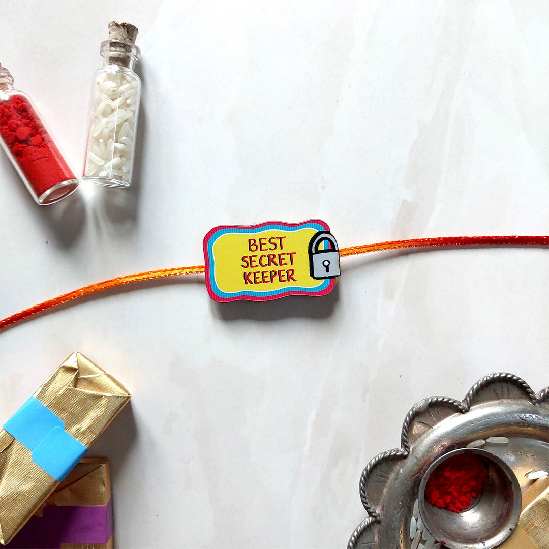 Glossy Printed Wooden 'Best Secret Keeper' Rakhi With Kumkum Rice For Brother