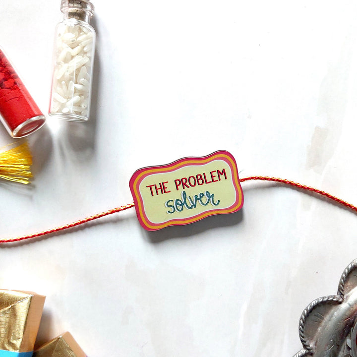 Glossy Printed Wooden 'Problem Solver' Rakhi With Kumkum Rice For Brother