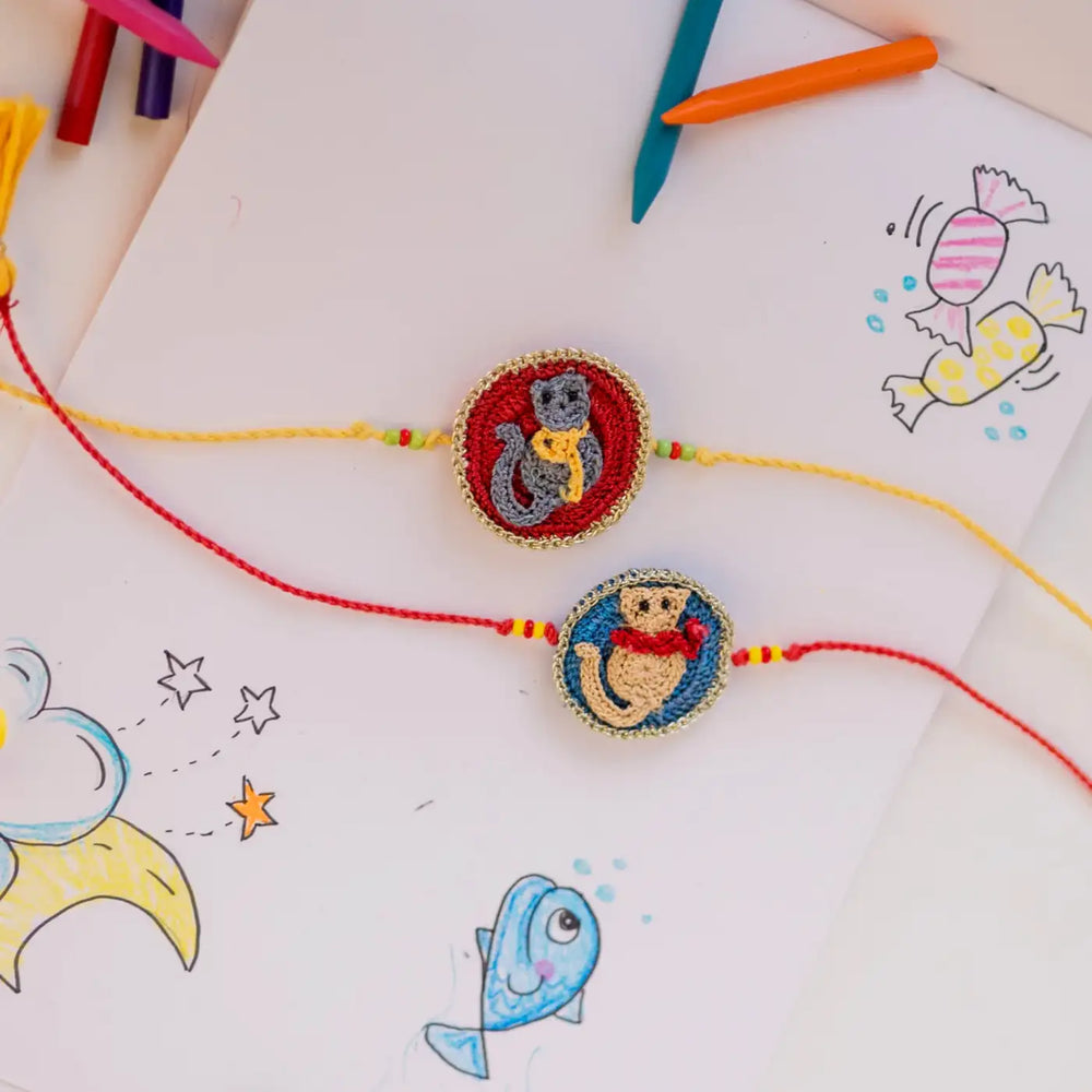 Handmade Crochet Kitten Theme Kids Rakhi With Roli Chawal Set Of 2 - Styled on Art Paper Background
