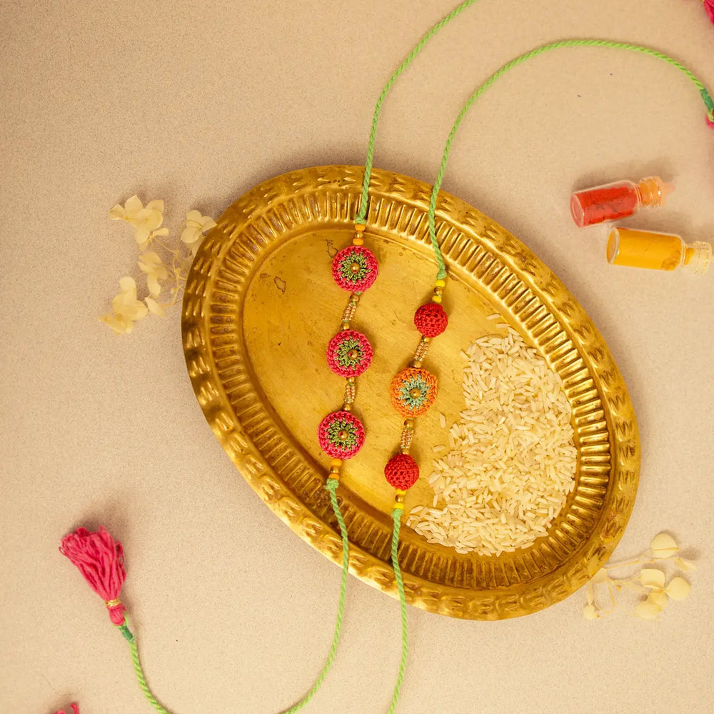 Handmade Crochet Multicolour Ananta Rakhi With Roli Chawal Set Of 2 - Top view of bracelets on tray