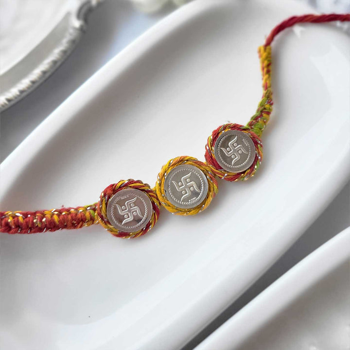 Handmade Three Swatik Coin Design Silver Rakhi Hamper With Roli Chawal For Brother - Angled view on white tray