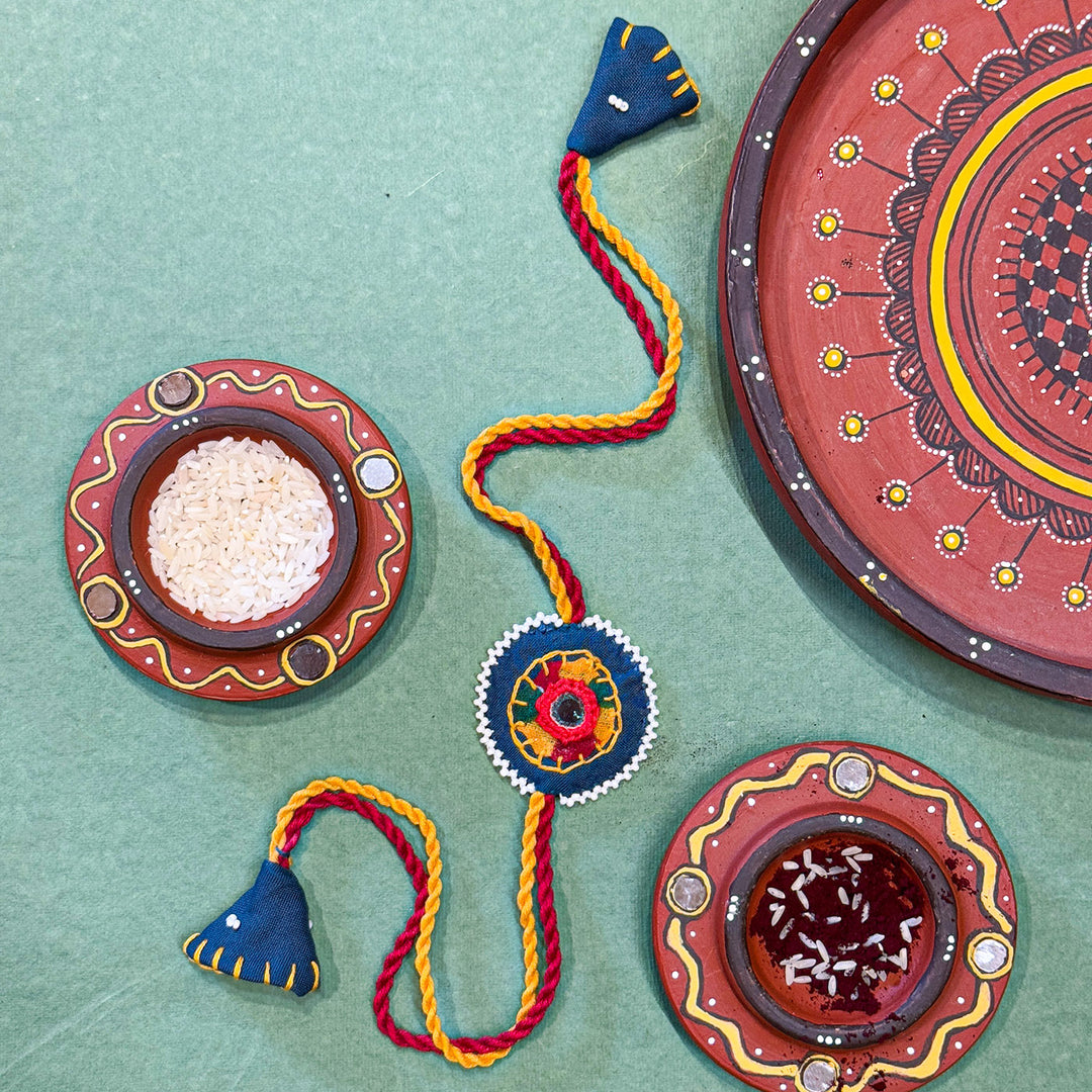 Reusable Mirror And Cotton Rope Rakhi For Brother - Product with decorative plates and powders arrangement