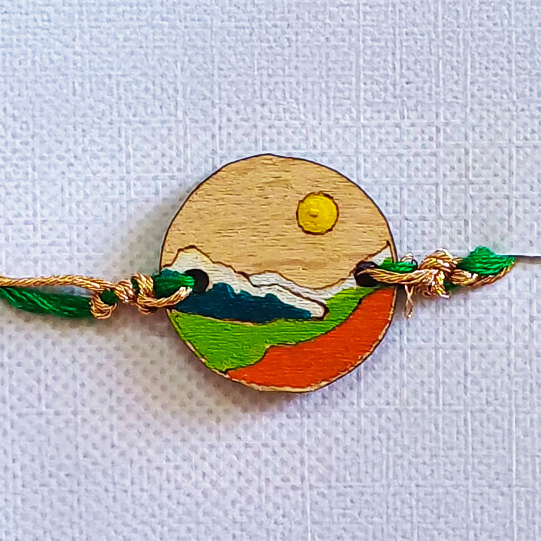 Handmade Mountain Sun And Snow Wooden Rakhi With Roli Chawal For Brother - Close-up Front View with Green Thread