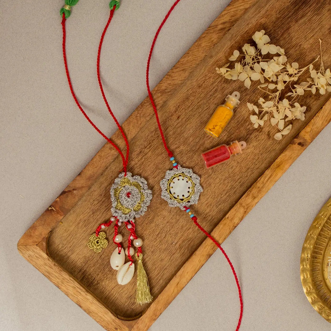 Handmade Crochet Sagar Seepi Bhaiya Bhabhi Rakhi With Roli Chawal Set Of 2 - Overhead view with decorative props