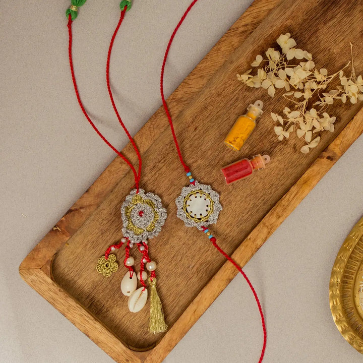 Handmade Crochet Sagar Seepi Bhaiya Bhabhi Rakhi With Roli Chawal Set Of 2 - Overhead view with decorative props