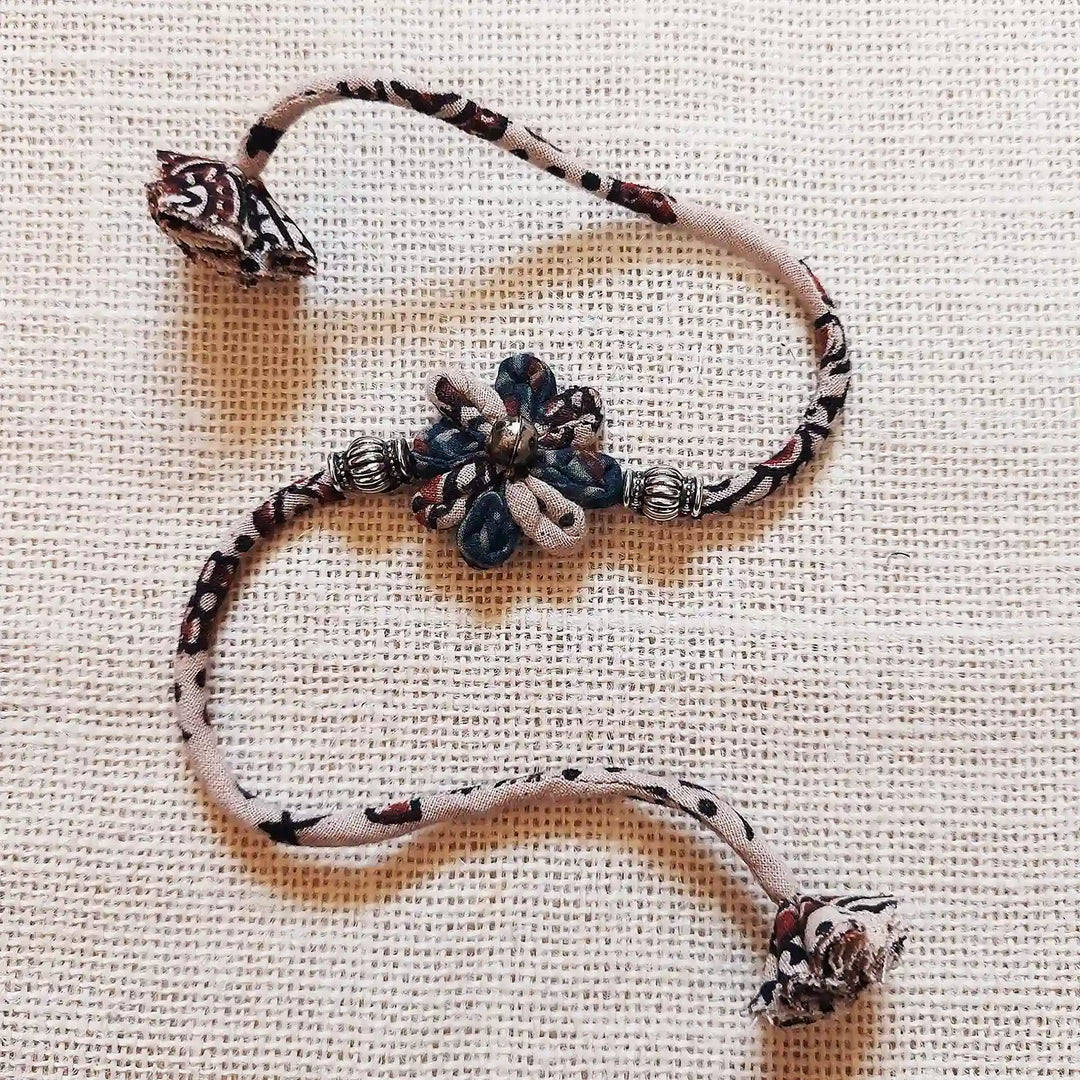 Handmade Dori Work Ajrakh Flower Rakhi With Roli Chawal - Textured Background Display