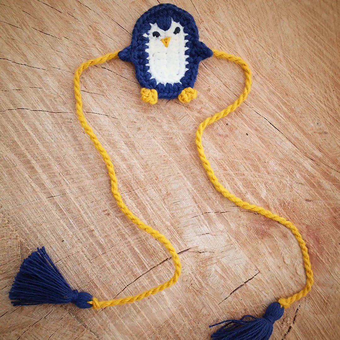 Handmade Crochet Penguin Theme Kids Rakhi And Toy Combo With Roli Chawal Set Of 2 - Flat Lay of Accessory with Tassels