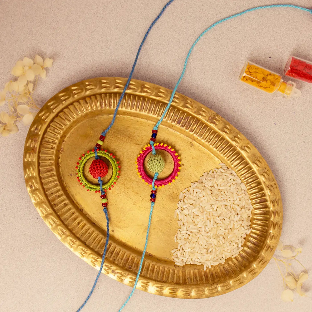 Handmade Crochet Fanaa Rakhi With Roli Chawal Set Of 2 - Top View on Gold Plate