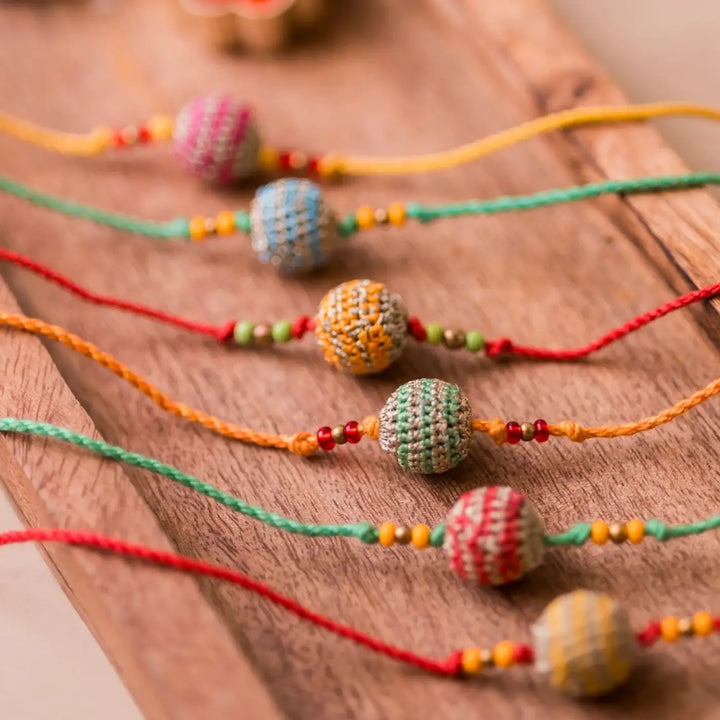 Handmade Crochet Multicolour Lined Suraj Rakhi With Roli Chawal Set Of 6 - Angled view of bracelets