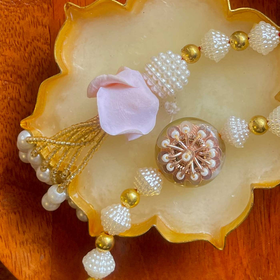 Handmade White And Gold Flower Design Pearl And Stone Bhaiya Bhabhi Rakhi - Close-up of decorative beads
