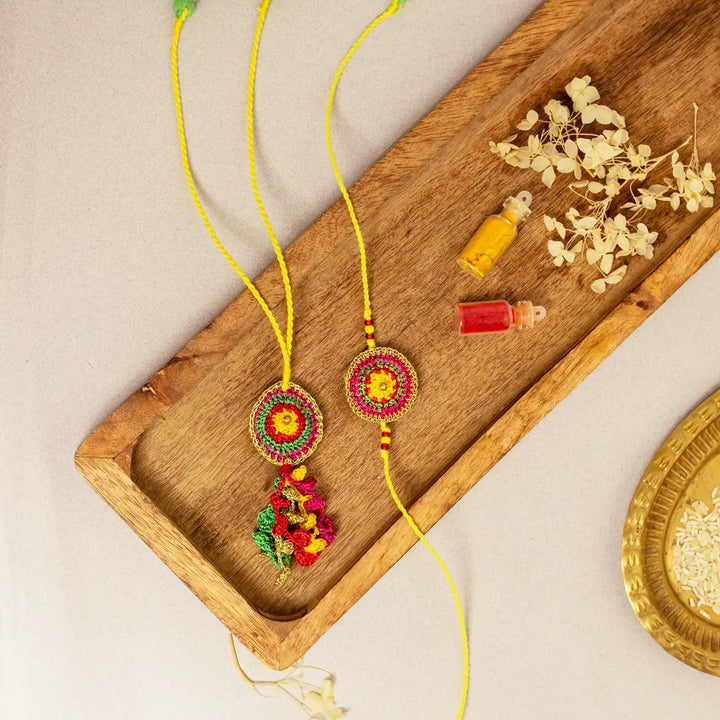 Handmade Crochet Rangeeli Bel Bhaiya Bhabhi Rakhi With Roli Chawal Set Of 2 - Styled Flat Lay with Decorative Items