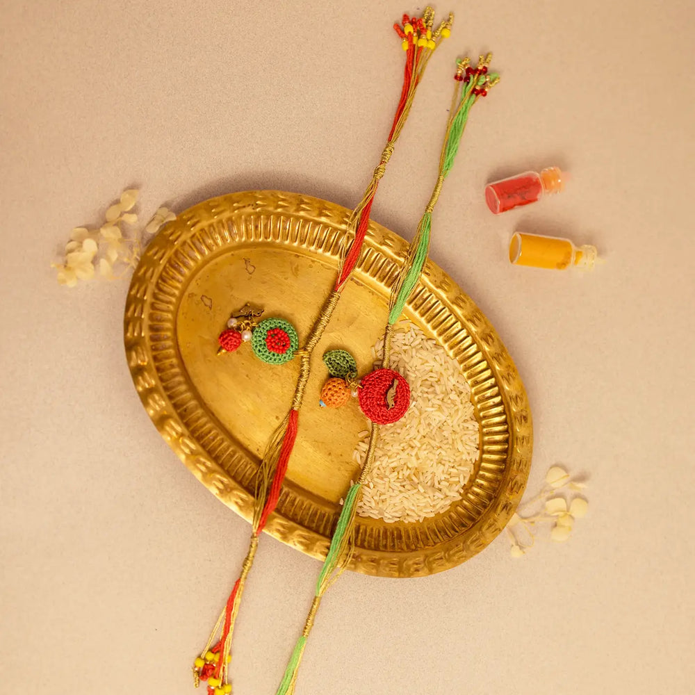 Handmade Crochet Ananya Flower And Golden Bird Rakhi With Roli Chawal Set Of 2 - Angled View with Decorative Tray