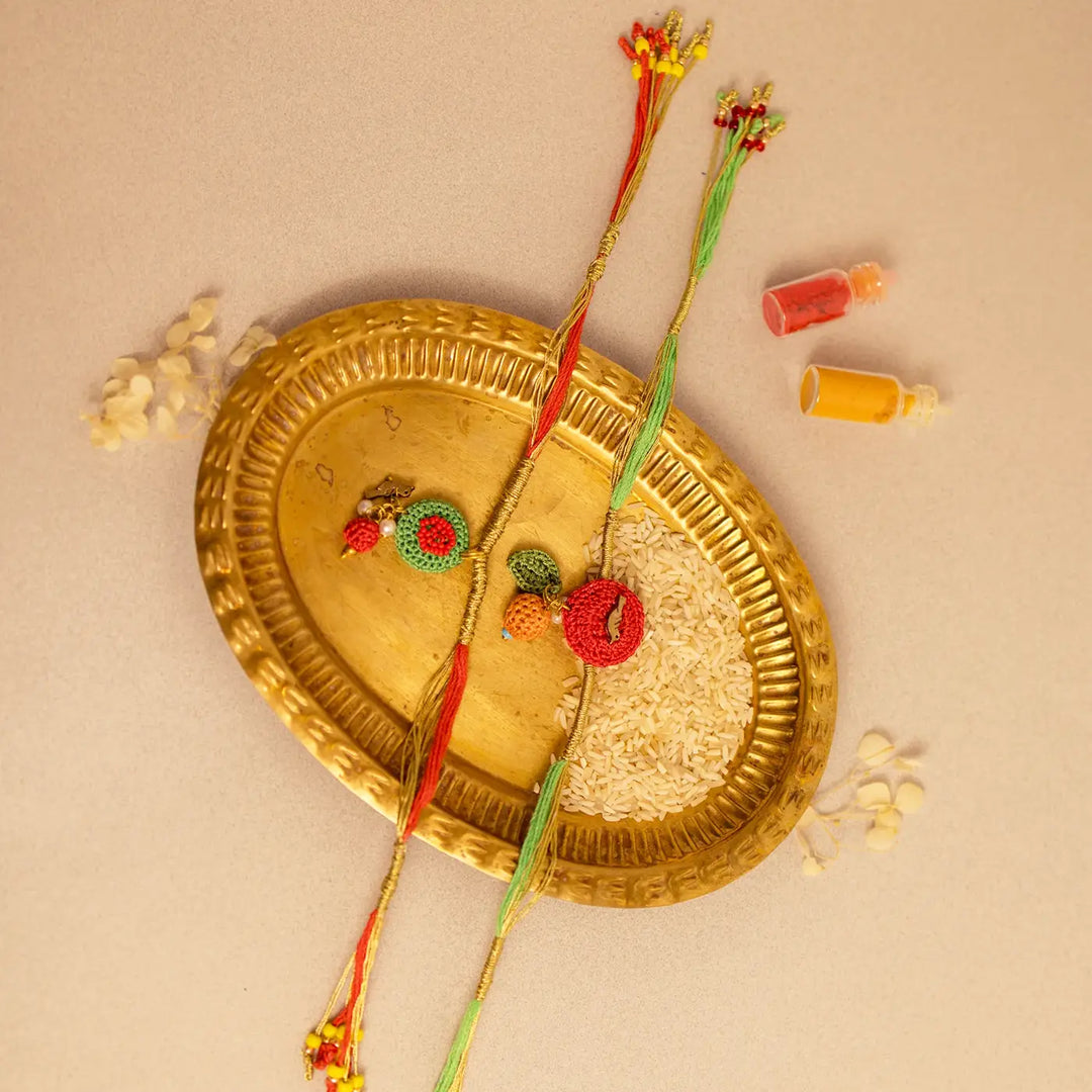 Handmade Crochet Ananya Flower And Golden Bird Rakhi With Roli Chawal Set Of 2 - Angled View with Decorative Tray