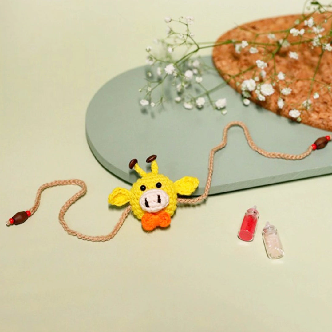 Handmade Crochet Giggling Giraffe Kids Rakhi With Roli Chawal - Flat Lay with Decorative Props