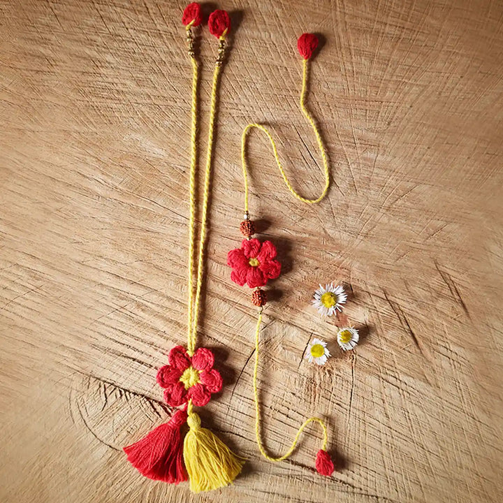 Handmade Crochet Red Flower Bhaiya Bhabhi Rakhi With Roli Chawal Set Of 2 - Necklace Laid Flat with Daisies