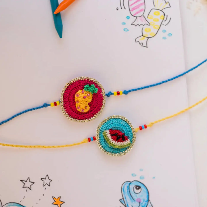 Handmade Crochet Fruits Theme Kids Rakhi With Roli Chawal Set Of 2 - Close-up Styled Flat Lay