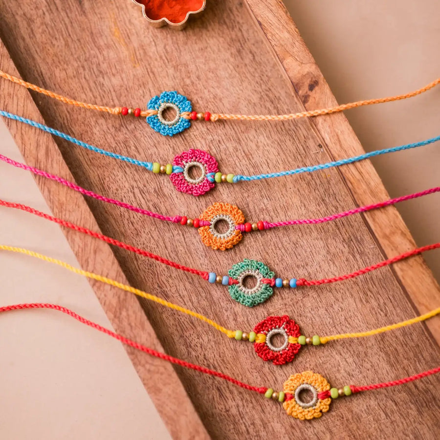 Handmade Crochet Rainbow Flowers Rakhi With Roli Chawal Set Of 6 - Top View Laid on Wooden Tray