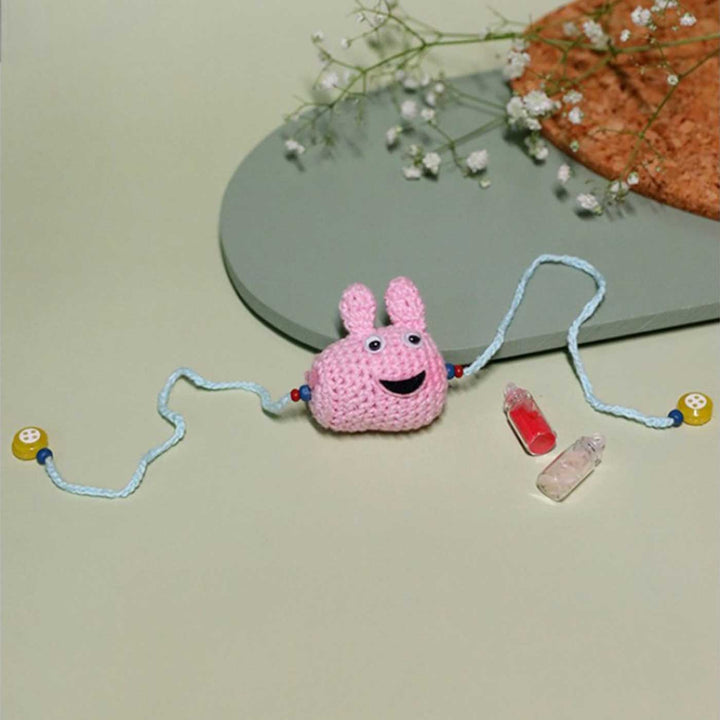 Handmade Crochet Peppa Pig Kids Lumba Rakhi With Roli Chawal - Flat Lay Showing Full Length