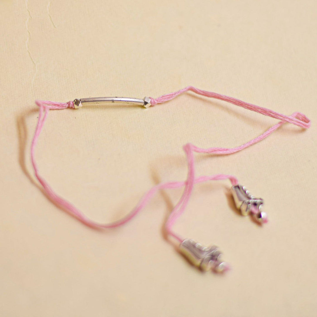 Handmade Stake Board Shoe And Pearl Design Rakhi With Roli Chawal - Pink string bracelet flat lay