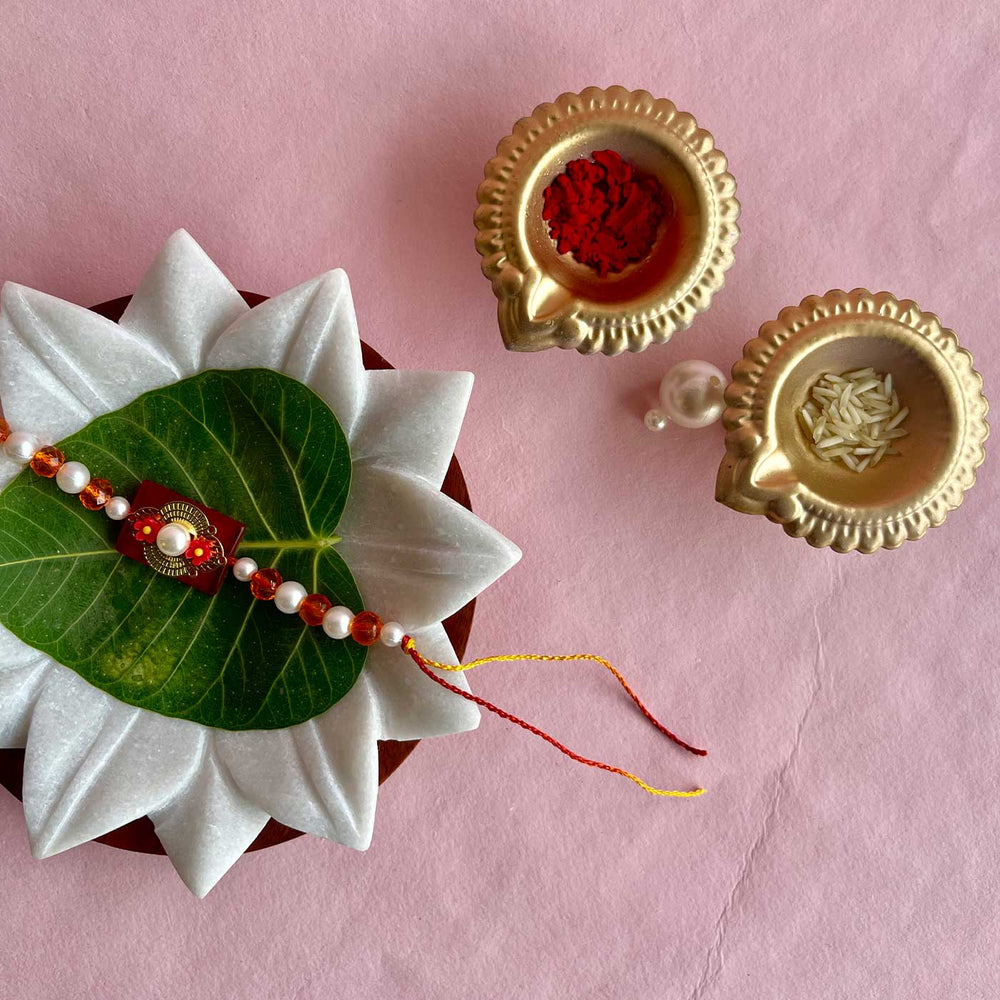 Handmade Flower Design Pearl And Stone Bhaiya Bhabhi Rakhi - Styled with traditional pooja items arrangement