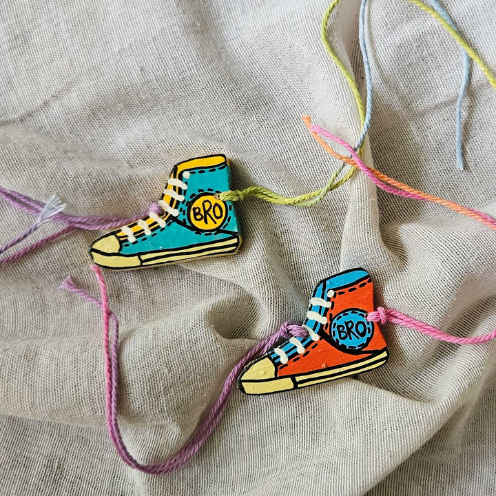 Handpainted Quirky Wooden Rakhi With Roli Chawal 12 - Two shoe rakhis on fabric