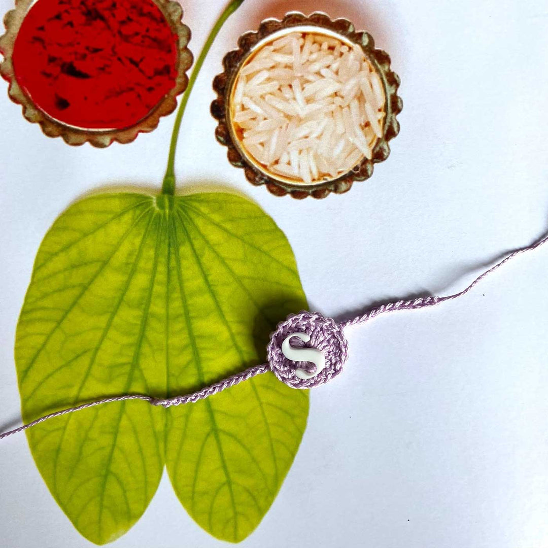 Personalized Handmade Crochet Round Shape Cotton Rakhi With Roli Chawal - Flat Lay with Decorative Items Background