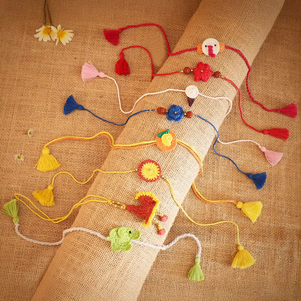 Handmade Crochet Multicolor Family Rakhi With Roli Chawal Set Of 8 - Overhead view of multiple Rakhis